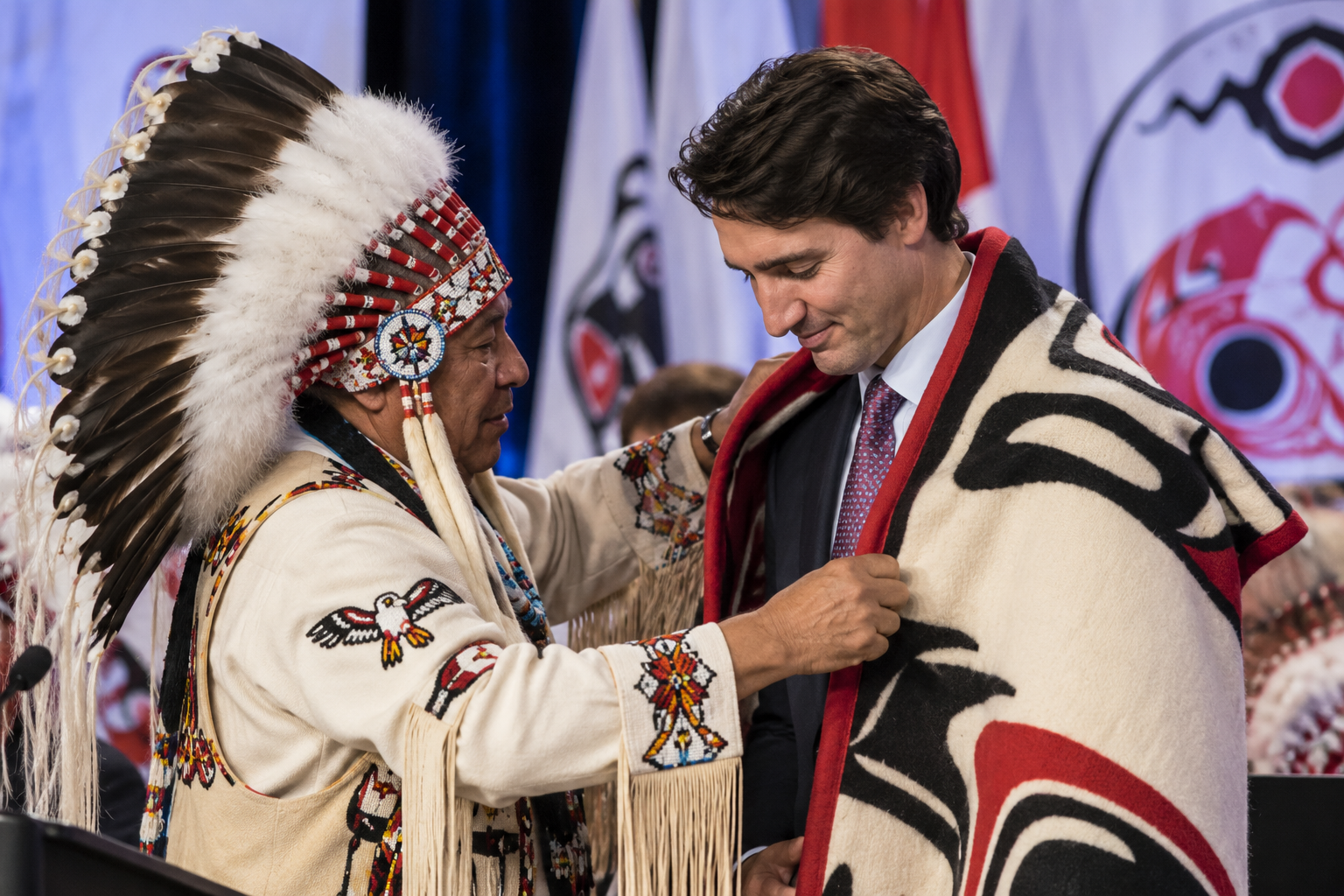 AFN National Chief Perry Bellegarde adjusts a blanket presented to Canada's Prime Minister Justin Trudeau following speeches at the Assembly of First Nations Special Chiefs Assembly in Gatineau, Quebec, Tuesday Dec. 8, 2015.