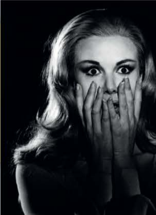 A terrified woman with both hands over her mouth